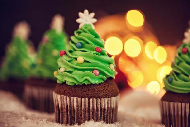 Chocolate cupcakes with green icing in the shape of a Christmas tree.