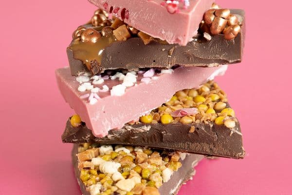 inclusion chocolate stacked on top of each other with a pink background