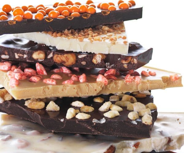 Slabs of milk, white and dark chocolate bites stacked on each other with various colourful inclusion toppings.