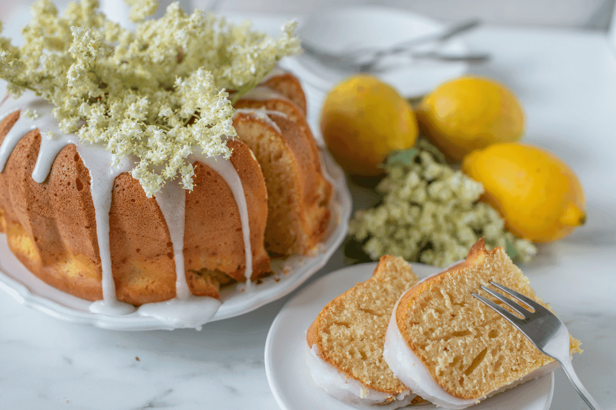 eldeflower summer cake with two slices and some lemon in the background